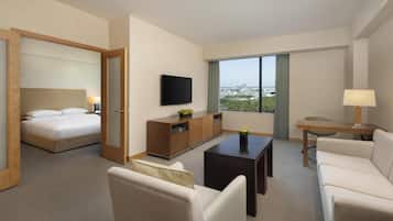 A hotel room with a bed, a TV, a desk, a sofa, and a view of the city.