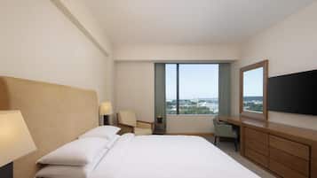 Une chambre d’hôtel avec un grand lit, un bureau, une chaise, une télévision et une vue sur la ville.