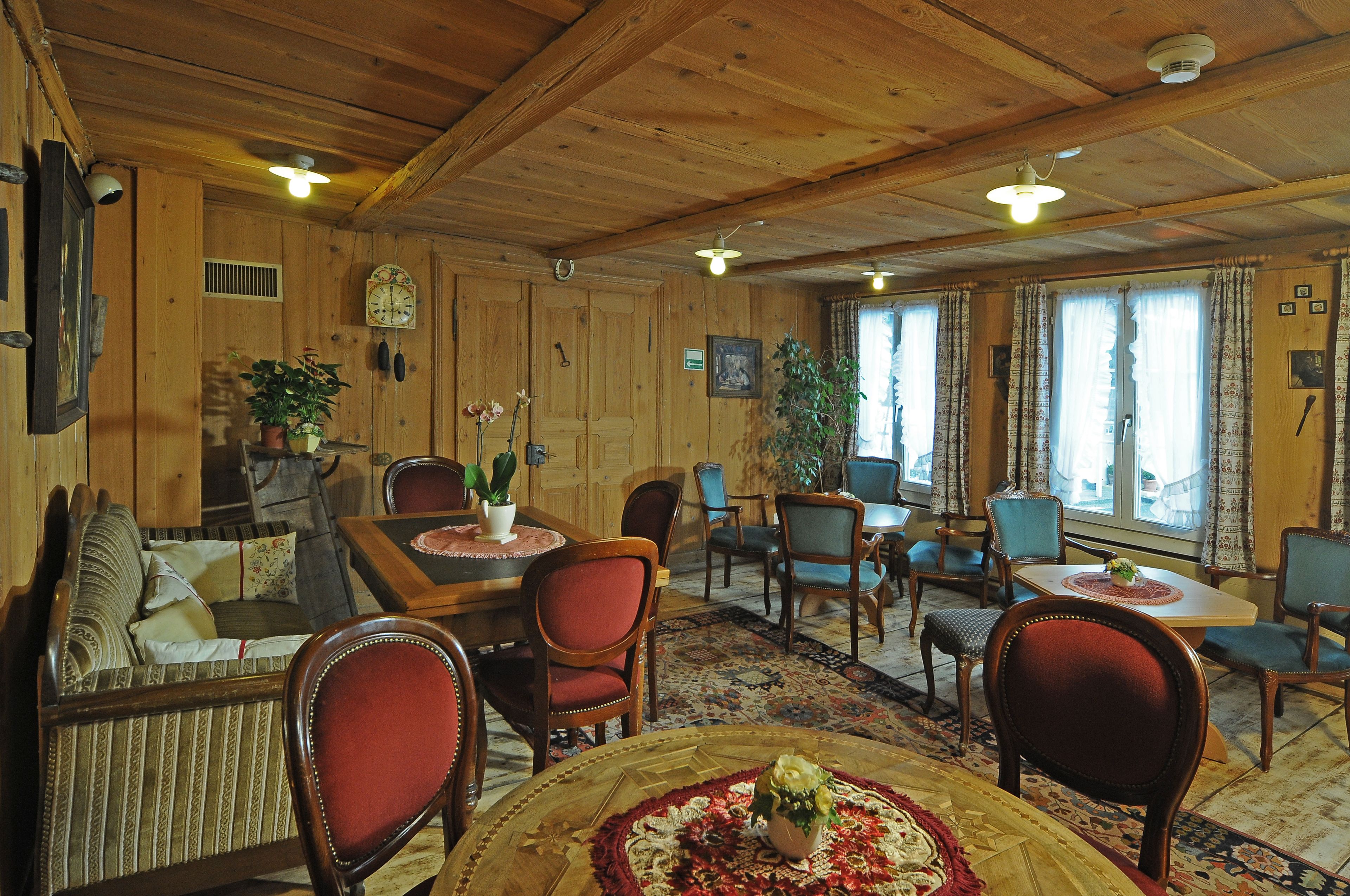 A cozy wooden interior with a dining area, sofas, and chairs.