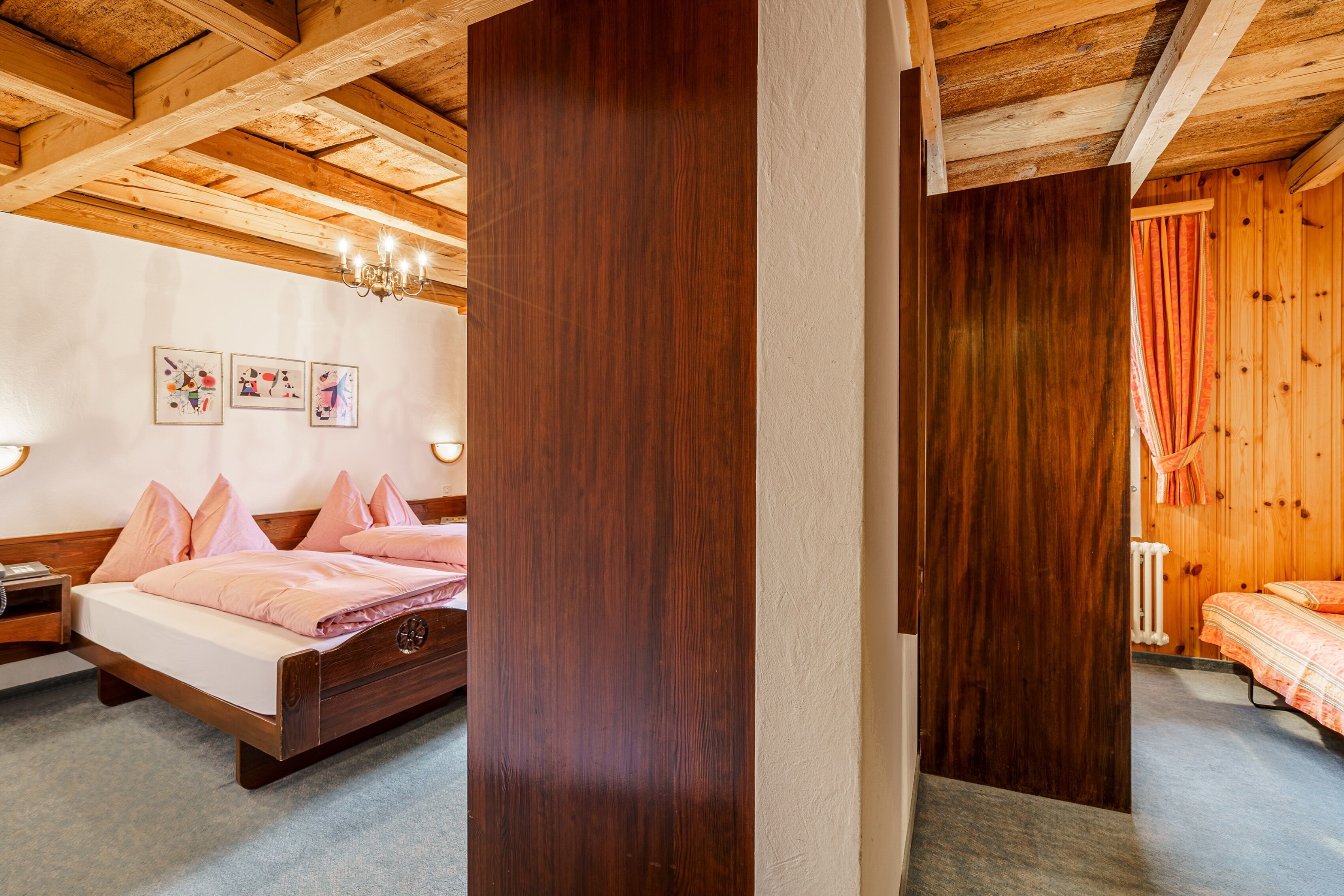 Une chambre avec un plafond en bois, un lit avec une literie rose et une table de chevet.