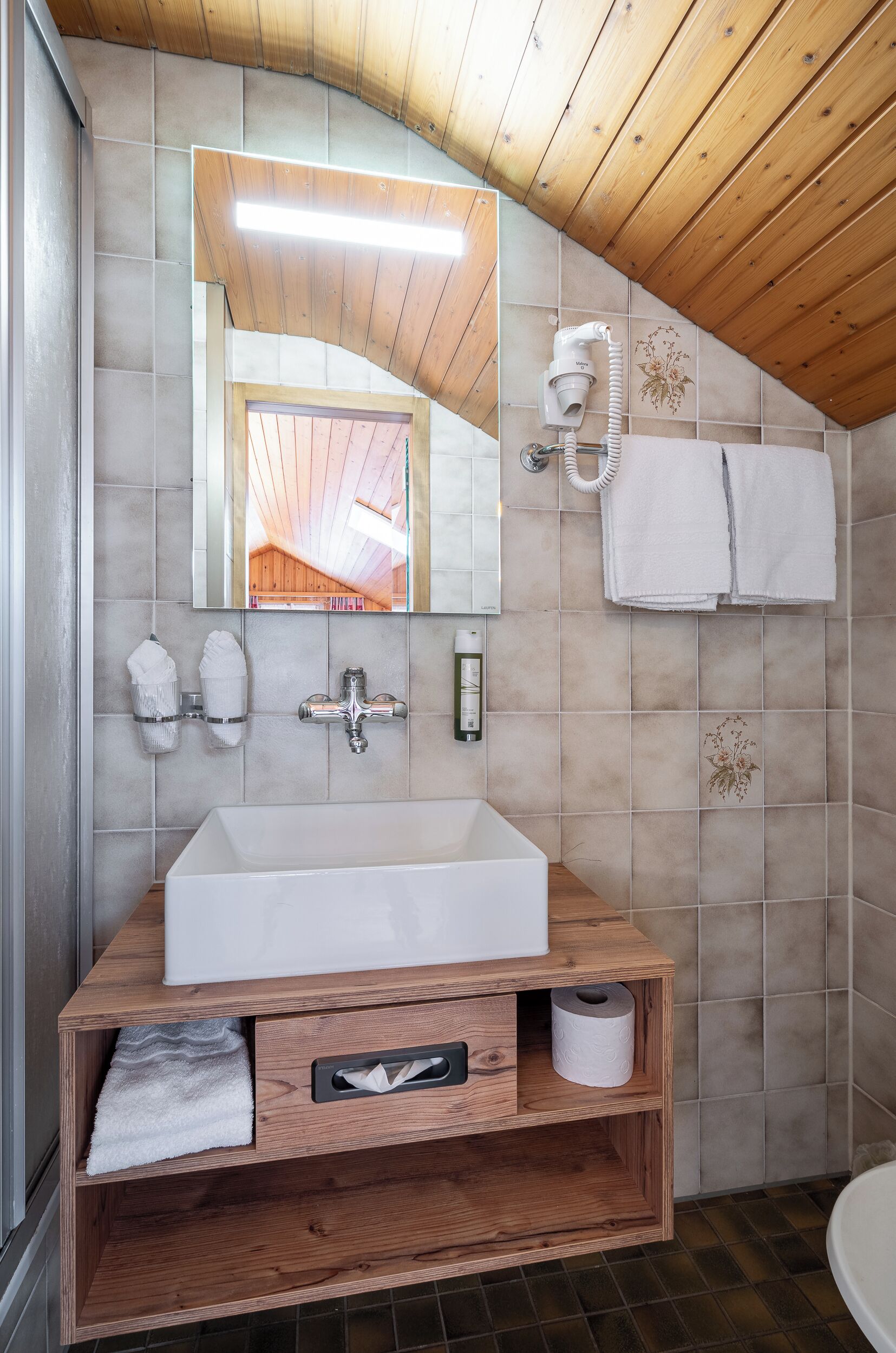 Un baño moderno con un mueble de tocador de madera, un espejo grande y un perchero para toallas.