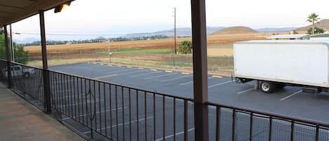 A covered parking area with a view of a white truck and distant hills.