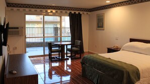 Habitación de hotel con cama, escritorio, silla, mesa y ventana con vistas al exterior.