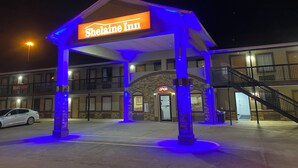 A hotel entrance with a sign reading "Shelaine Inn" under a covered area with blue lighting. - Shelaine Inn (Jeffersonville)