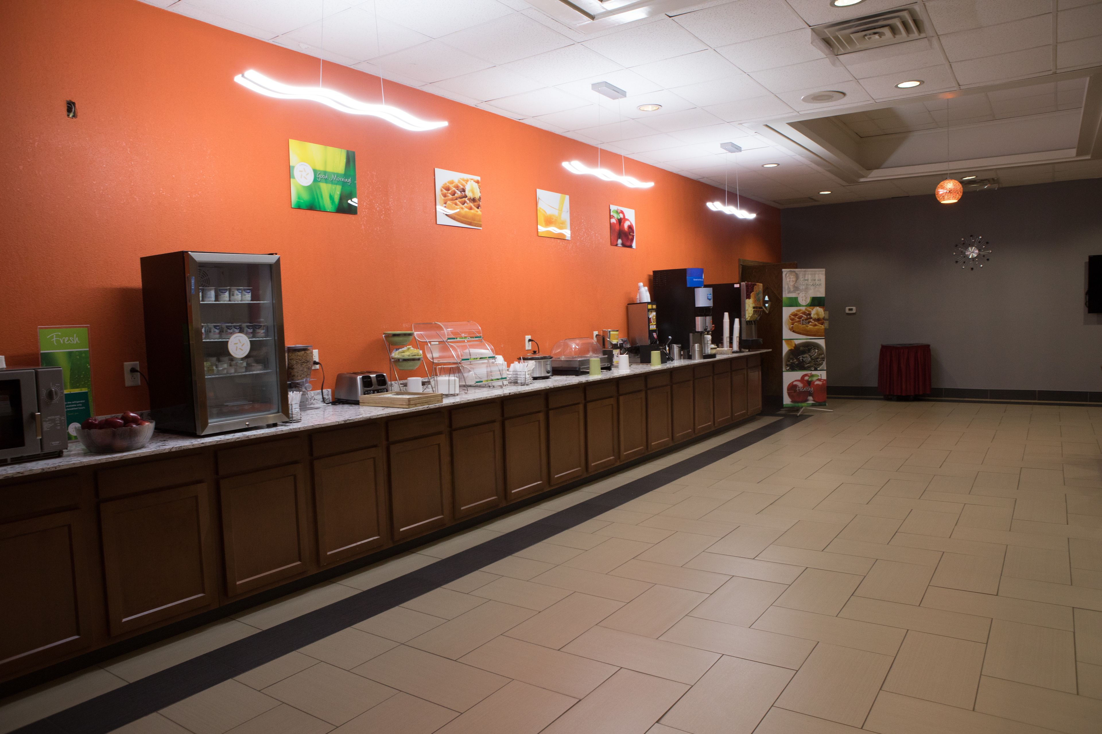 A long counter with a refrigerated display case, a coffee machine, and a beverage dispenser.