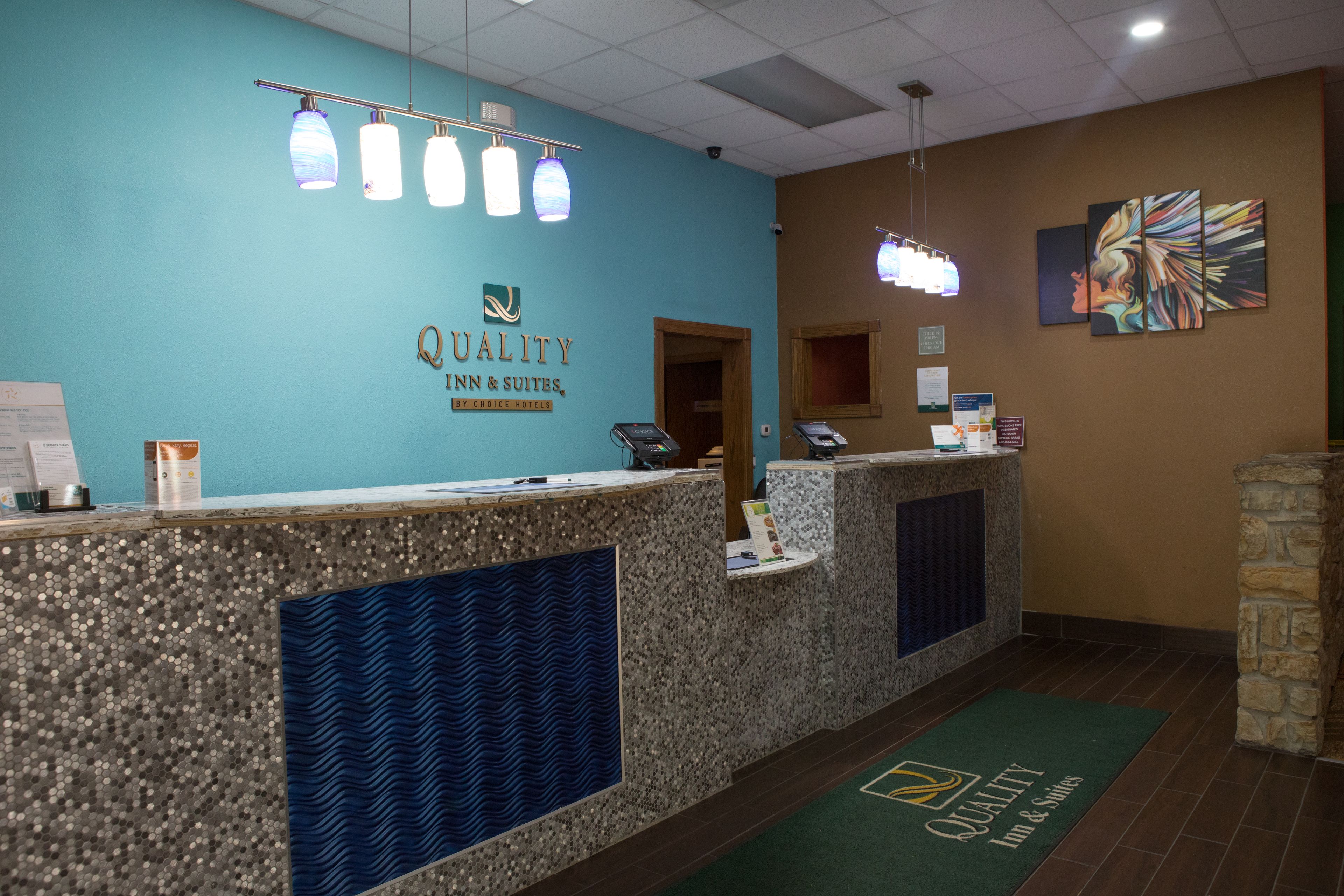 A reception area with a teal wall, a reception desk, and a stone pillar.