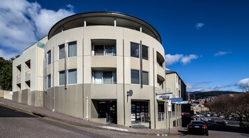 A modern building with a curved facade, multiple balconies, and a clear sky.