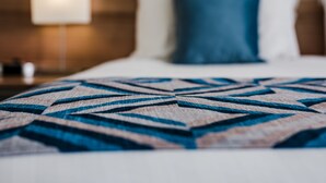 A bed with a geometric patterned blanket, a wooden headboard, and a bedside lamp. - Salamanca Terraces (Battery Point)