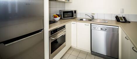 Een moderne keuken met roestvrijstalen apparatuur, waaronder een koelkast, magnetron, oven en vaatwasser.