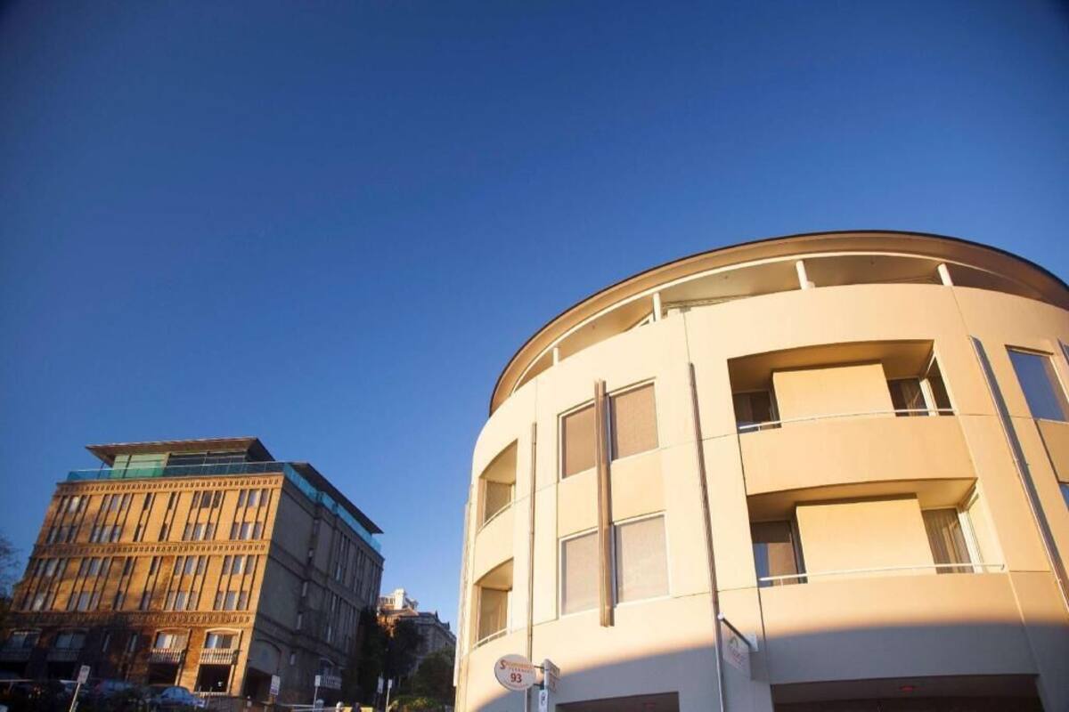 A building with a curved facade, multiple windows, and a sign indicating a parking area.
