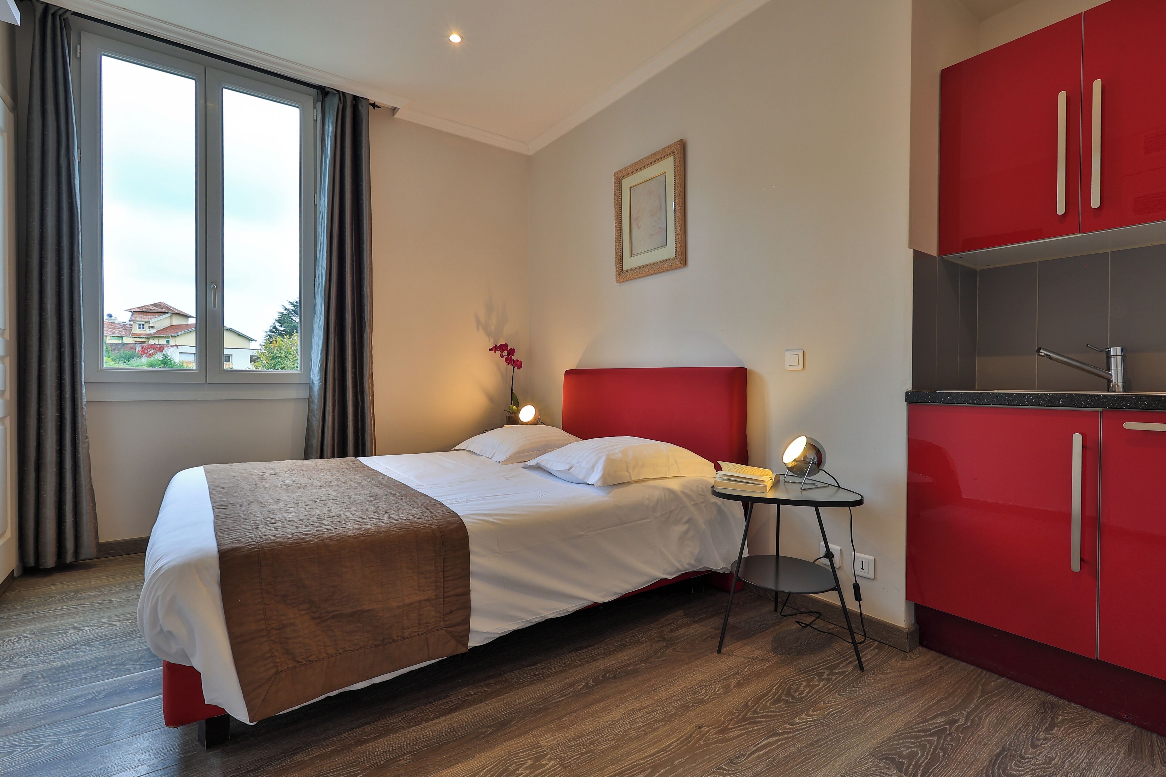 Un dormitorio moderno con cama, mesita de noche y armarios rojos.