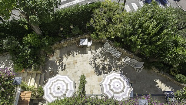 Un área de estar al aire libre con sombrillas, un banco y una mesita.