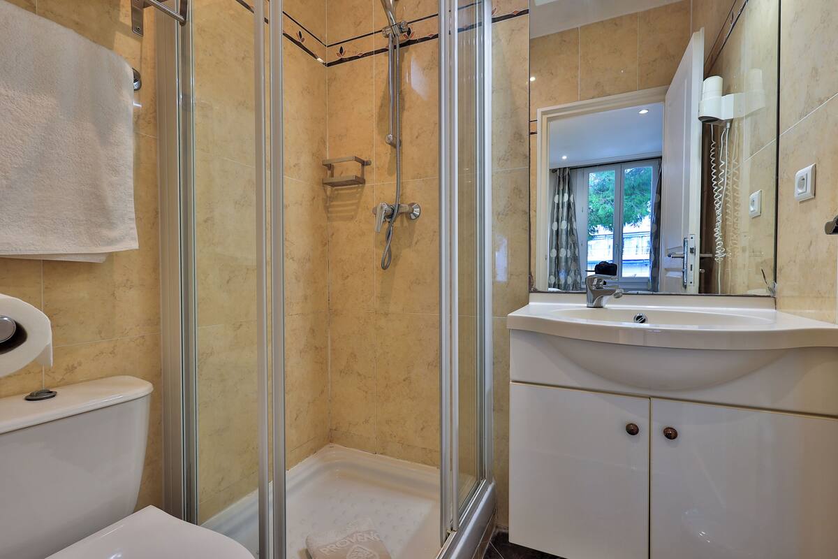 Un bany amb dutxa de vidre, un lavabo blanc i un vàter.