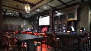A bar area with wooden furniture, a large screen, and a bar counter with a cash register. - Days Inn & Suites by Wyndham West Edmonton (Edmonton)