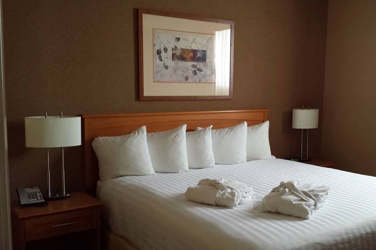 A hotel room with a bed, two bedside tables, a framed picture on the wall, and a window with curtains.