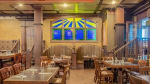 A restaurant with wooden tables and chairs, a stained glass window, and a staircase. - Days Inn & Suites by Wyndham West Edmonton (Edmonton)