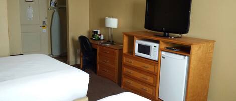 A hotel room with a bed, a desk with a television, a microwave, and a refrigerator.