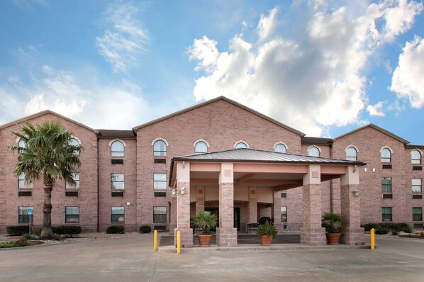 A multi-story brick building with a covered entrance and potted plants.