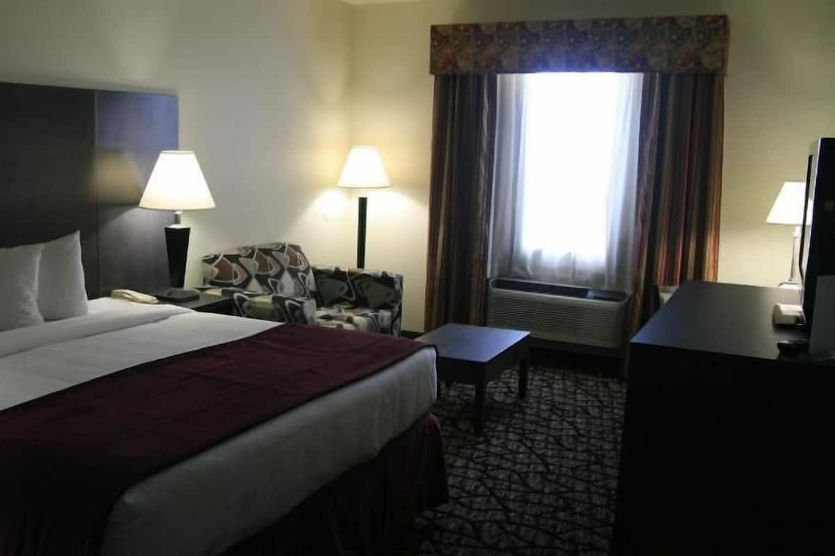Une chambre d’hôtel avec un grand lit, deux lampes de chevet, une chaise, un bureau et un téléviseur.