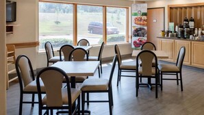 A restaurant with multiple tables and chairs, a counter with various items, and a large window with a view of the outside.