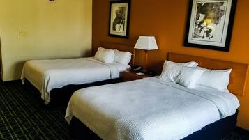 A hotel room with two beds, a nightstand with a lamp, and two framed pictures on the wall.