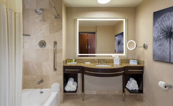 A modern bathroom with a bathtub, a shower with a handheld showerhead, a vanity with a sink and mirror, towel racks, and a dandelion artwork on the wall.