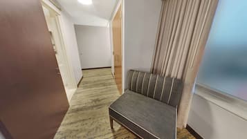 En gang med sofa, en trædør og et vindue med gardiner.