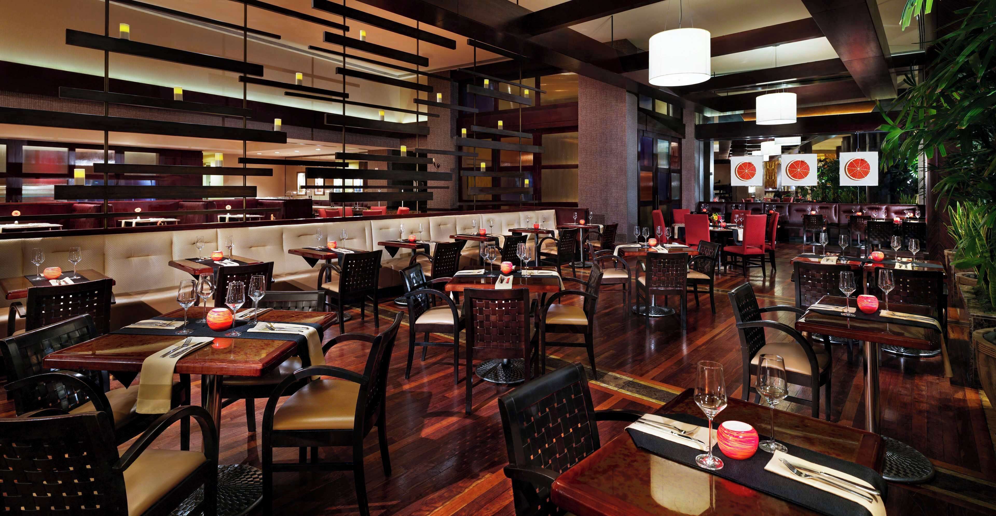 Restaurante com várias áreas de refeição, mesas e cadeiras de madeira.
