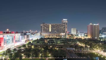 A modern hotel with a prominent Hilton sign, surrounded by lush greenery and a water feature.