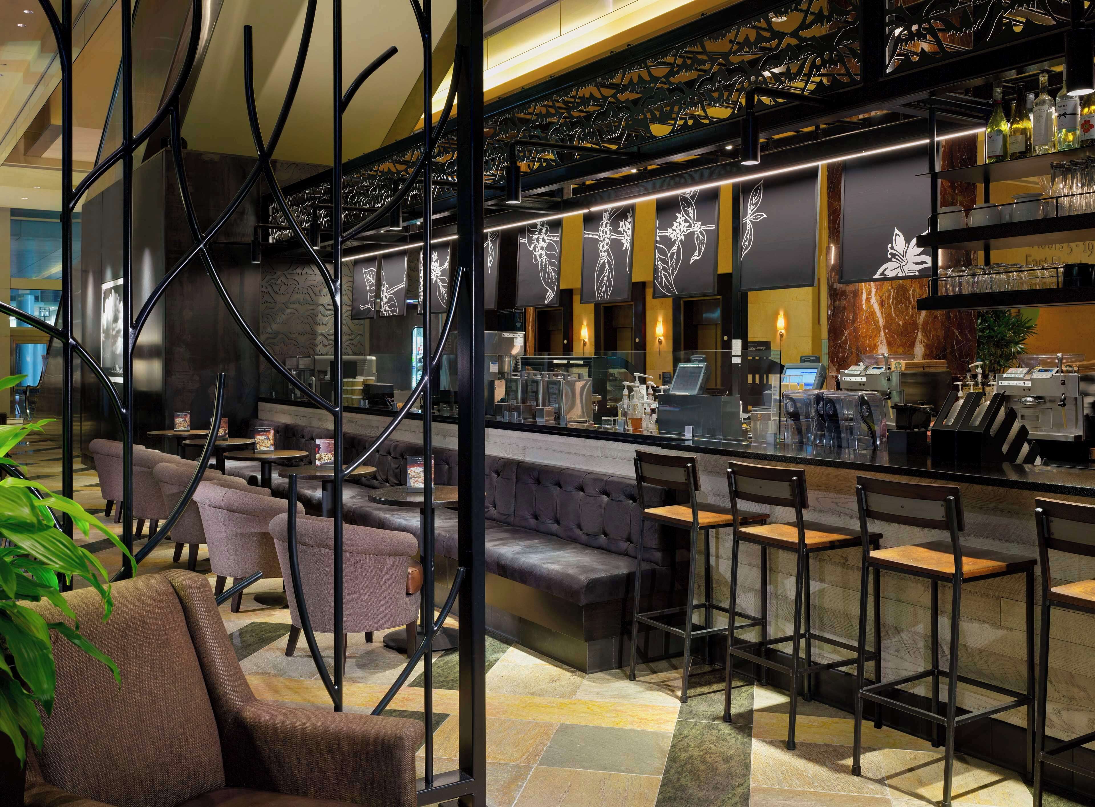 A modern bar area with seating, a counter, and a decorative wall with leaf patterns.