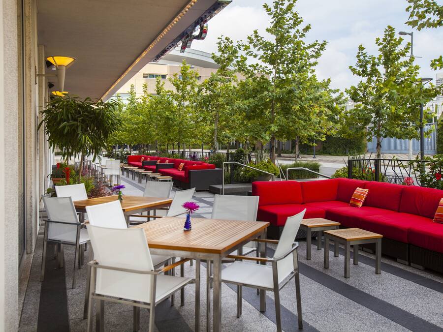 Un espace extérieur aménagé avec des tables et des chaises, un canapé rouge et des plantes en pot.
