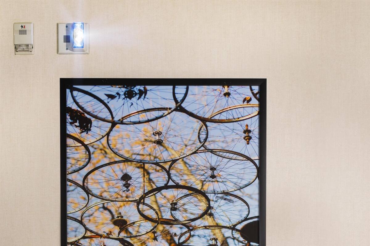 A framed artwork of bicycles on a wall, a desk with a lamp, and a chair.