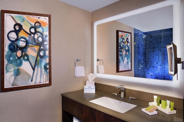 A bathroom with a sink, mirror, towel rack, and a framed abstract painting.