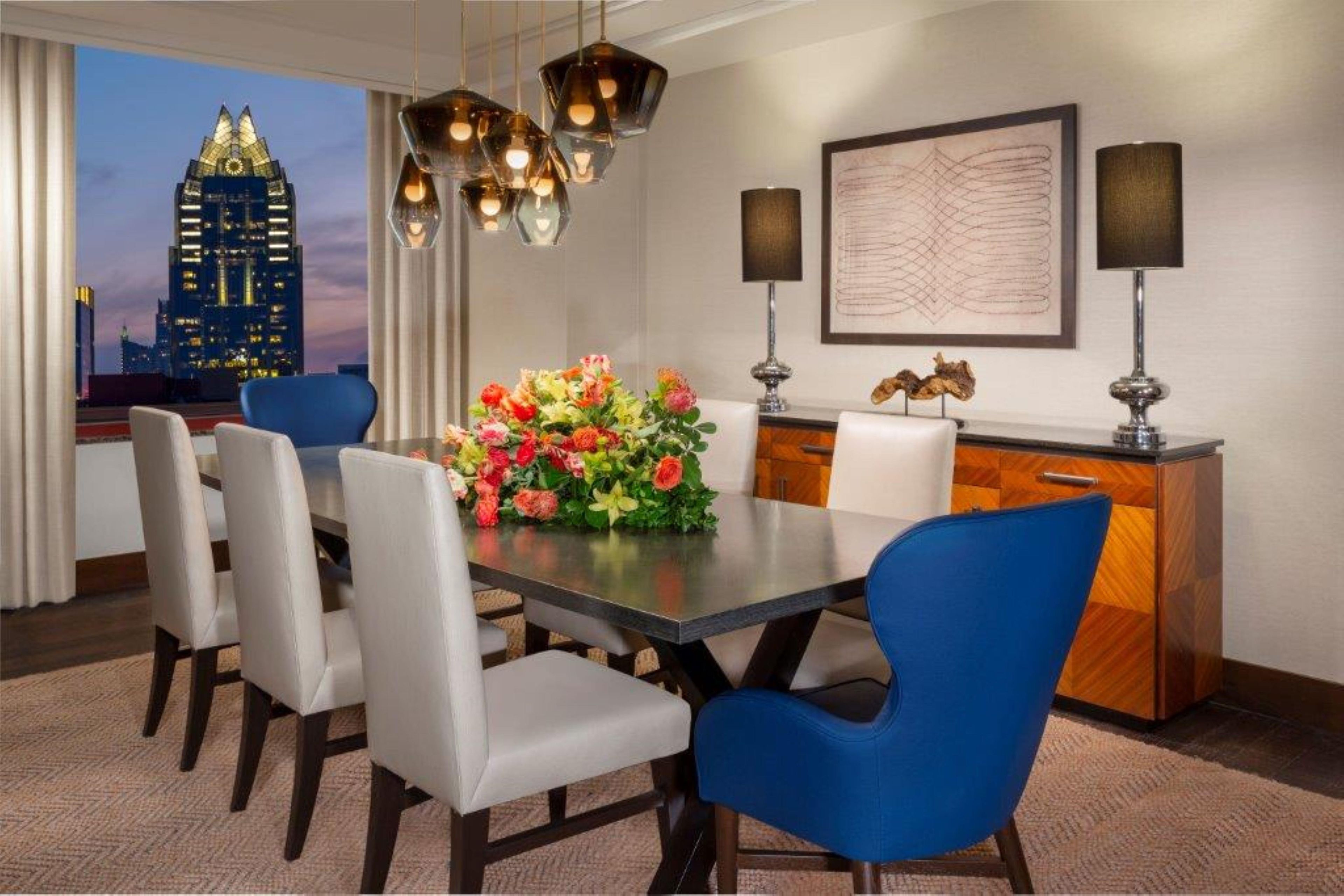 Comedor con mesa, sillas, un florero, vistas de la ciudad y una lámpara moderna.