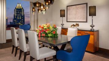 A dining area with a table, chairs, a vase of flowers, a cityscape view, and a modern chandelier.