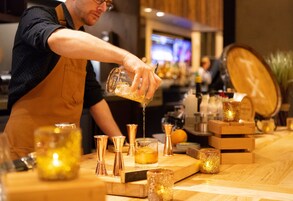 A bartender pouring a drink into a glass.