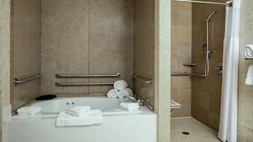 A bathroom with a bathtub, a shower, and handrails.