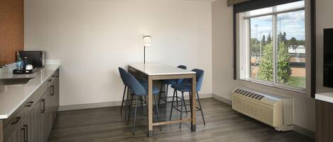 Una cocina moderna con una mesa de comedor, sillas, una estufa integrada y un amplio ventanal con vistas al exterior.