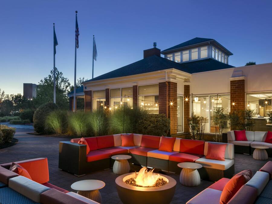 An outdoor seating area with a fire pit, sofas, and tables.