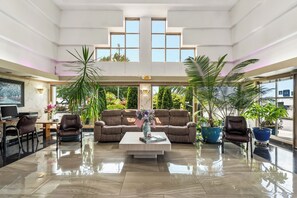 A spacious lobby with a high ceiling, a central seating area with a sofa and chairs, and large windows offering views of the outdoors. - Americas Best Value Inn Phoenix Medford (Phoenix)