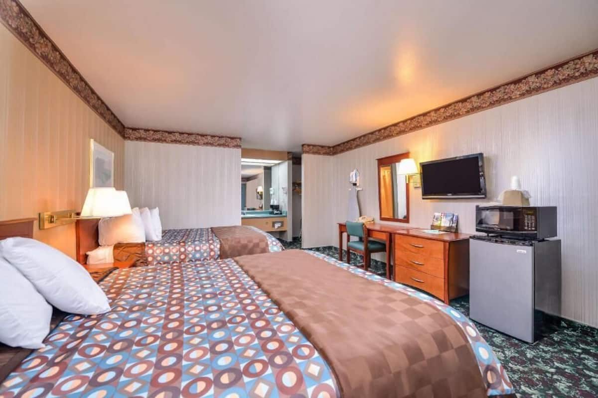 Une chambre d’hôtel avec un grand lit, un bureau avec un ordinateur, une télévision et un réfrigérateur.