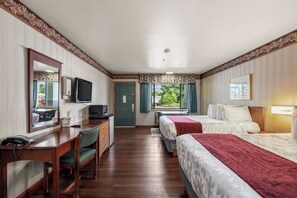 Une chambre d’hôtel équipée d’un bureau, de deux lits, d’une télévision et d’une fenêtre avec des rideaux.