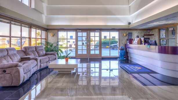 Un vestíbulo amplio con un sofá confortable, un mostrador de recepción y grandes ventanales con vistas al exterior.