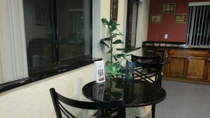 A dining area with a round glass table, black chairs, and a potted plant. - Scottish Inn & Suites (Houston)