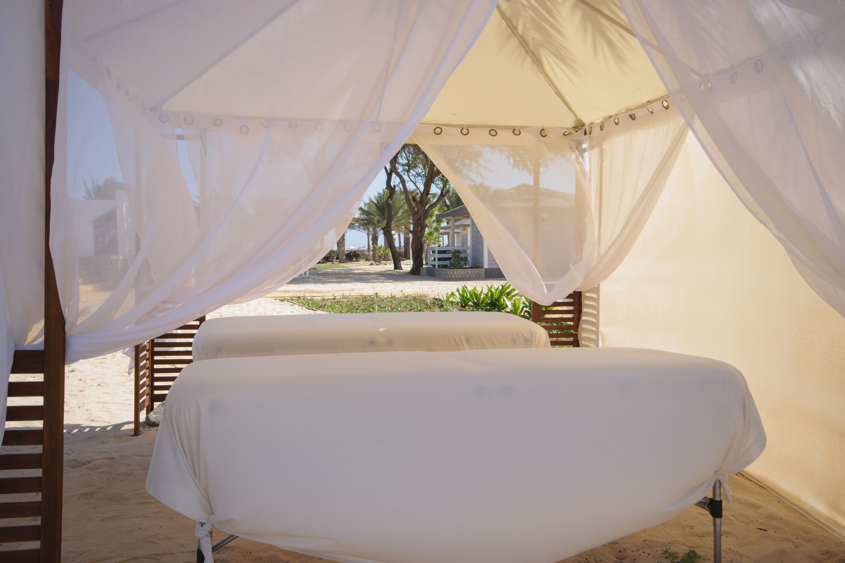 Zona de descanso al aire libre con carpa, cama y mosquitero.