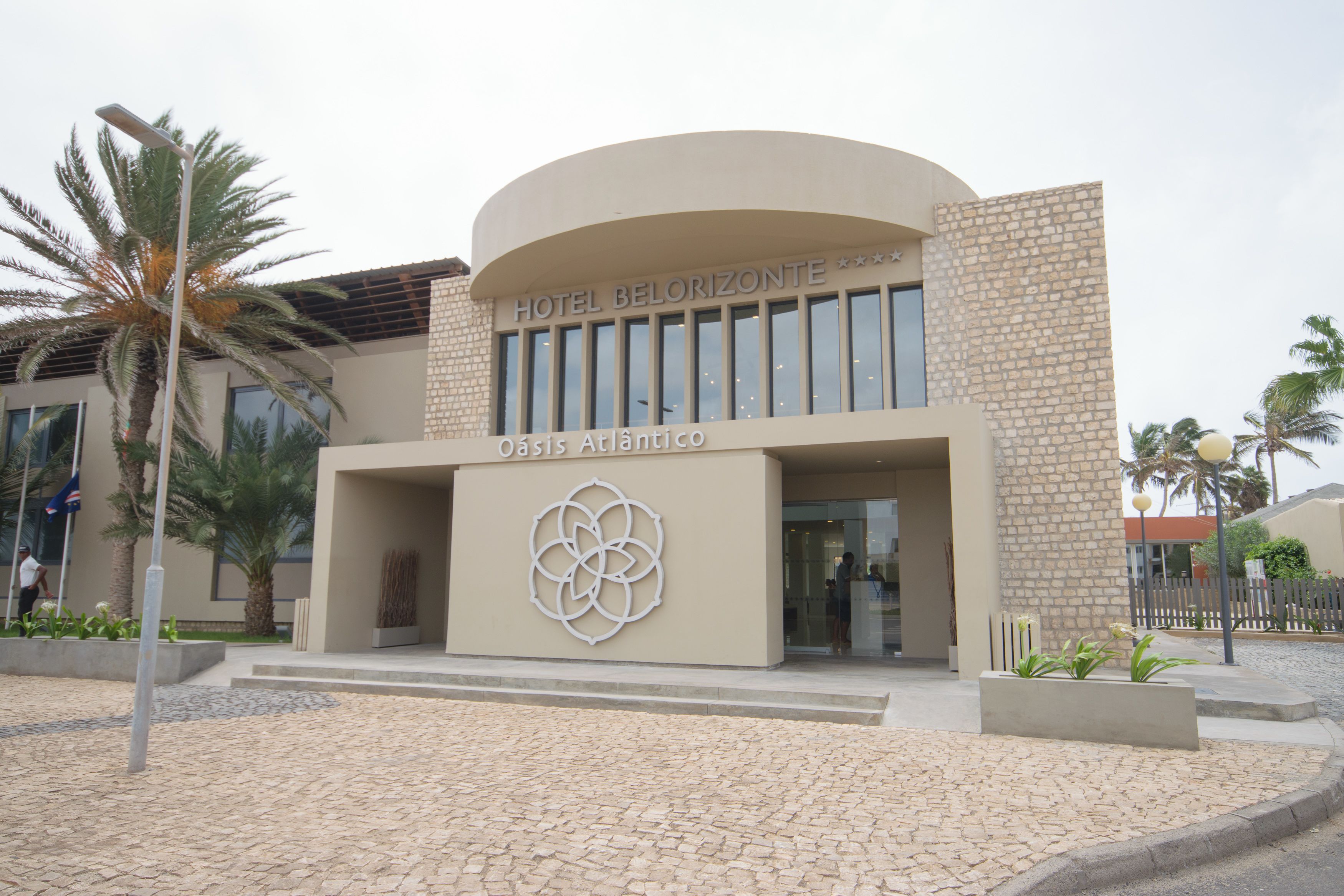 Un hotel moderno con fachada curva, logotipo destacado y pared con textura de piedra.