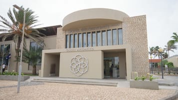 Un hotel moderno con fachada curva, logotipo destacado y pared con textura de piedra.