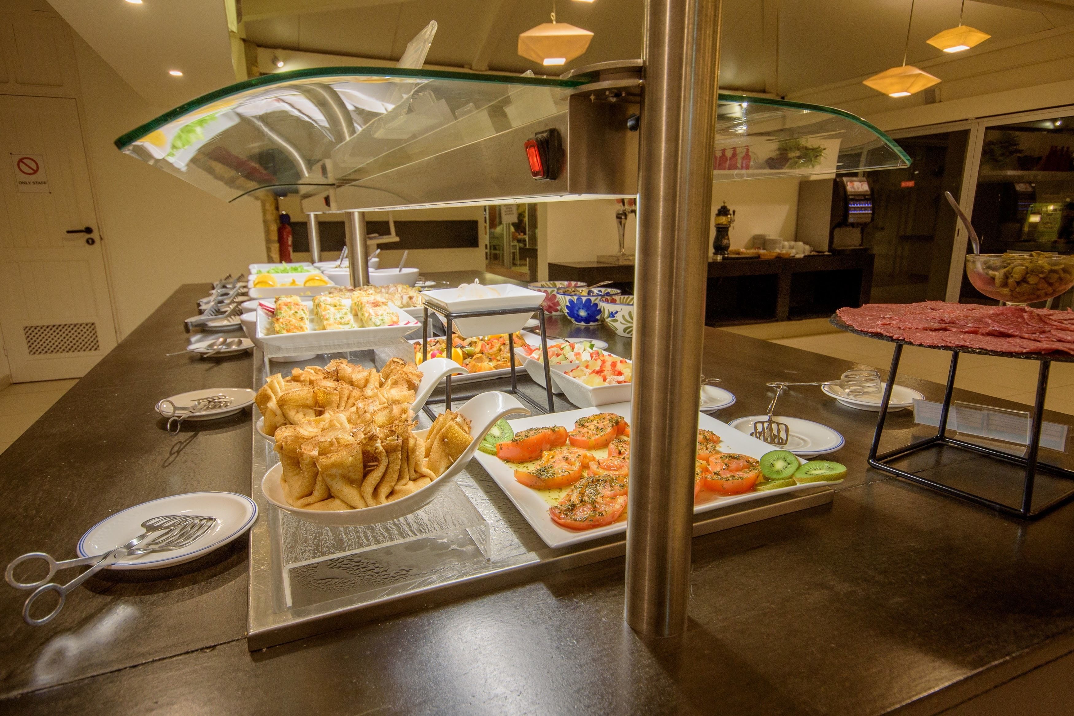 Un bufé con diferentes opciones de comida, incluyendo pan, ensaladas y un plato de carne.