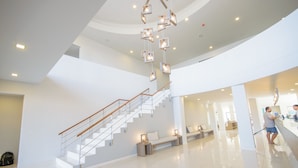 A spacious lobby with a modern staircase, a reception desk, and a seating area.