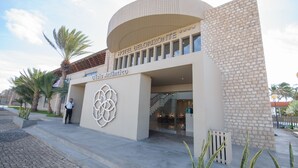 A modern hotel entrance with a circular design, a prominent logo, and a staircase leading inside.